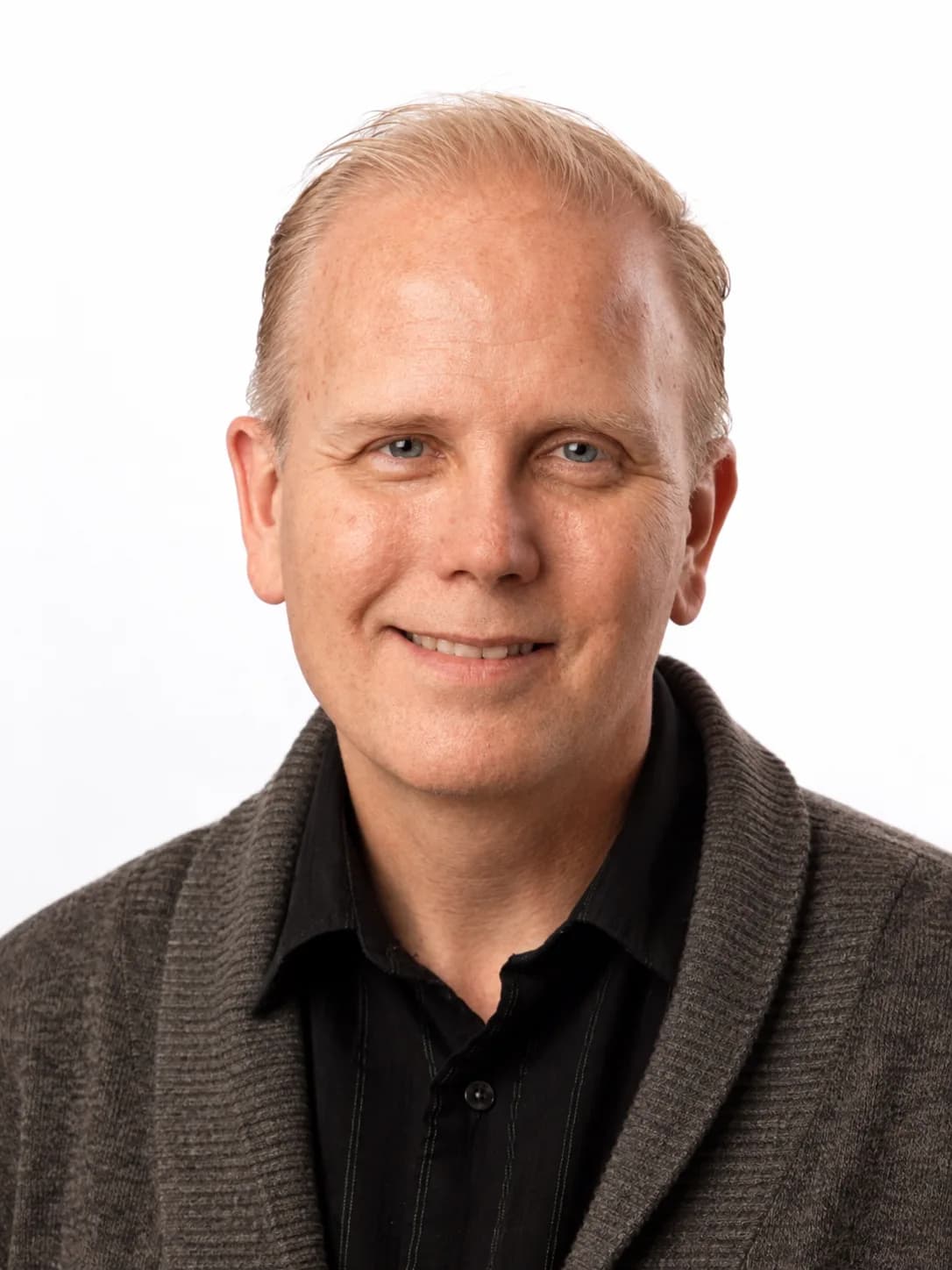 Studio portrait of Jamie Parsley in a grey shawl-collar cardigan over a black shirt